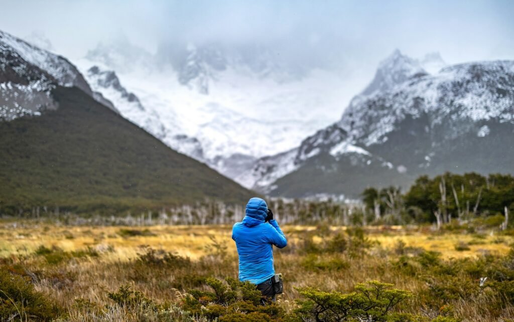 A person standing in a field with mountains in the background